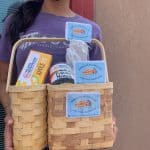 A woman holds a basket with apple pie, rice and beans