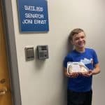 Young man holds up an apple pie outside Senator Joni Ernst's office